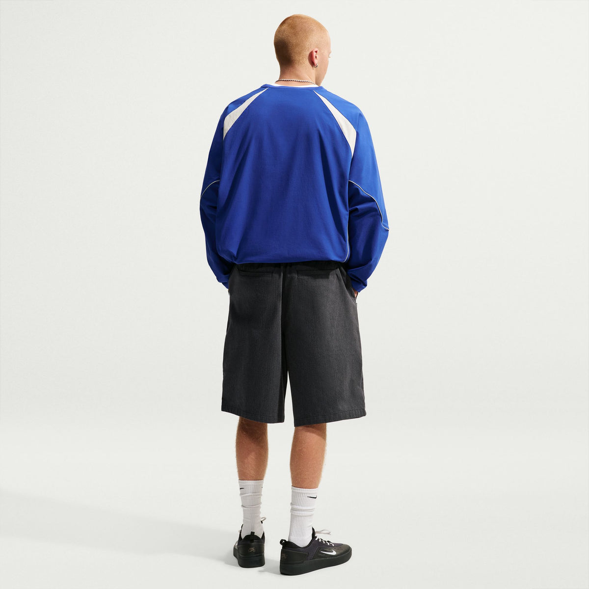 Nike SB Bagel Skate Shorts in Black / White, modelled rear outfit view with a blue long-sleeved top.